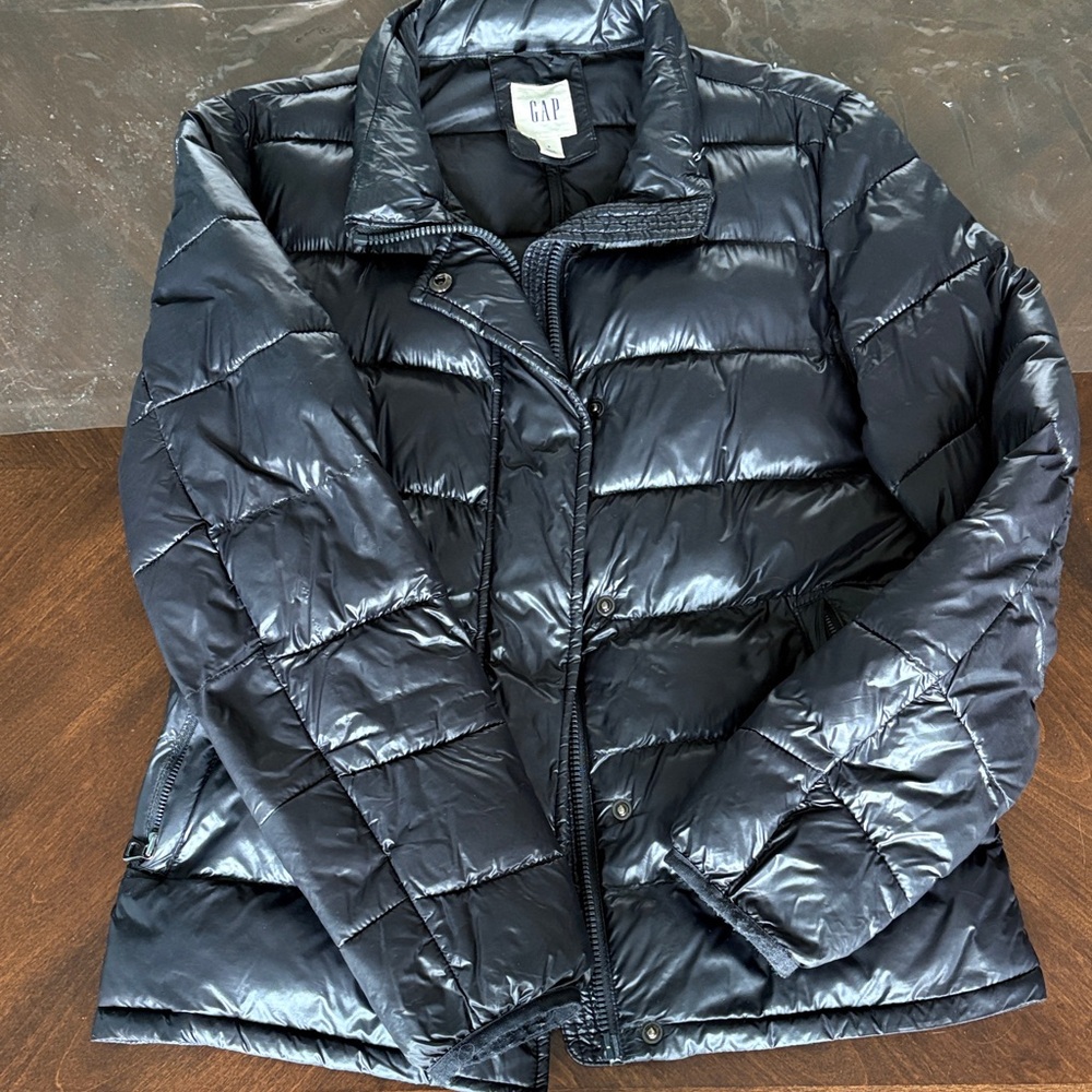 Black puffer jacket with zip and snaps. Primaloft filling.